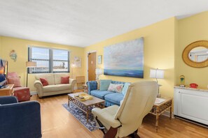 A living room with a sofa, armchairs, a coffee table, and a painting on the wall.