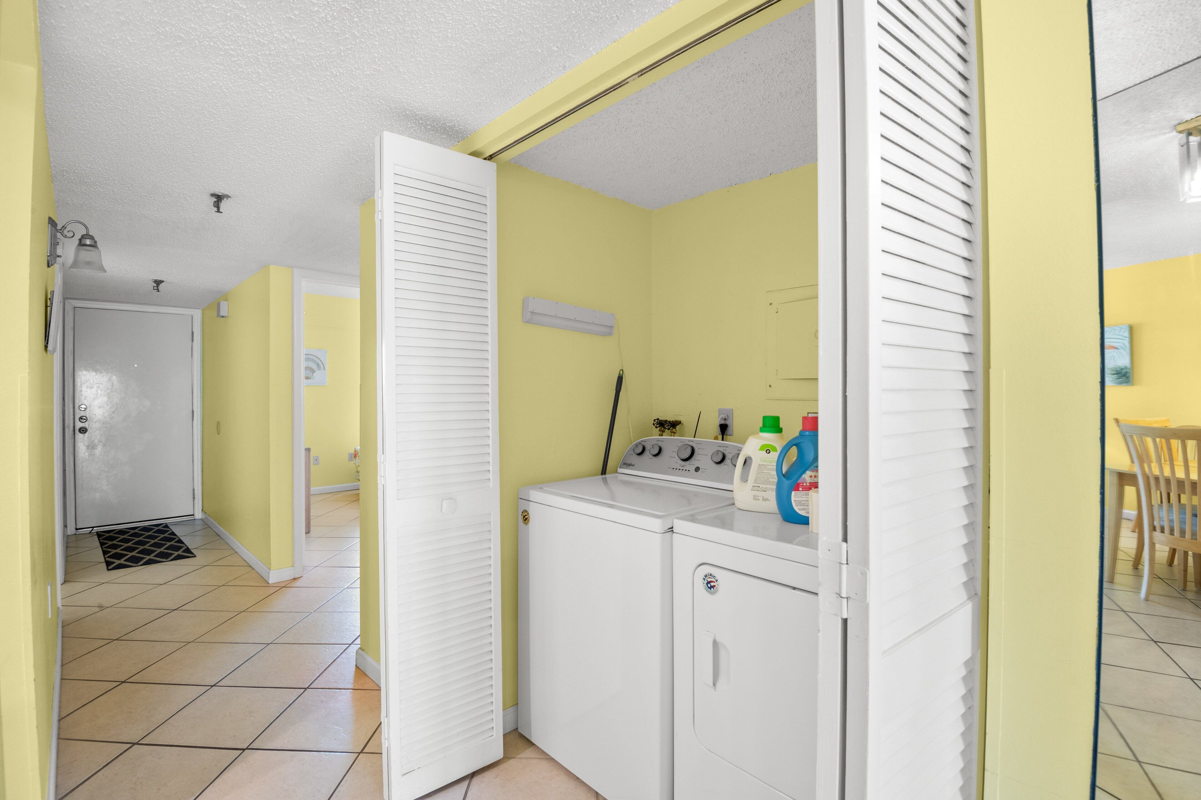 A laundry area with a washing machine and dryer, a utility room with a door, and a tiled floor.