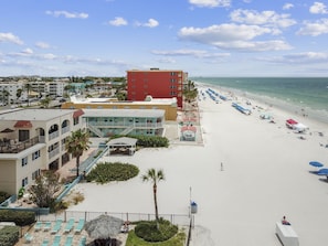 A beachfront hotel with multiple floors, a pool area, and beach umbrellas.