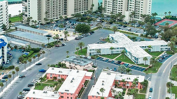 A coastal hotel area with multiple high-rise buildings, parking lots, and a beach in the background. -    🌅 Gulf Winds 2nd-Floor Condo — Gulf Views & Bright Beachside Charm (ST PETE BEACH)