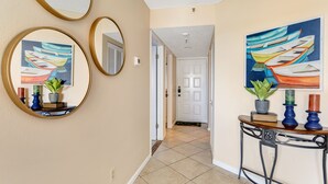 A hallway with three round mirrors, a wooden console table with a potted plant, and two paintings of boats. - 🌊 Caprice Resort Unit #203 – Gulf Front Serenity for Two in St. Pete Beach (St Pete Beach)