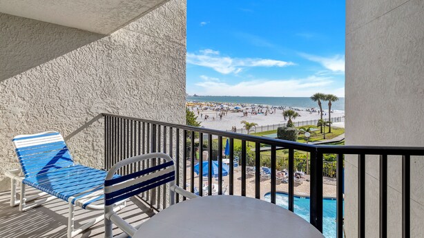 A balcony with a pool, a chair, and a view of a beach and ocean. - 🌊 Caprice Resort Unit #203 – Gulf Front Serenity for Two in St. Pete Beach (St Pete Beach)