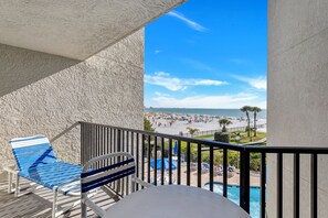 Un balcon avec une piscine, une chaise et une vue sur une plage et l’océan.