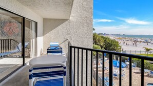 A balcony with a view of a beach, lounge chairs, and umbrellas. - 🌊 Caprice Resort Unit #203 – Gulf Front Serenity for Two in St. Pete Beach (St Pete Beach)