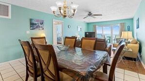 A dining area with a table, chairs, a chandelier, and a ceiling fan.