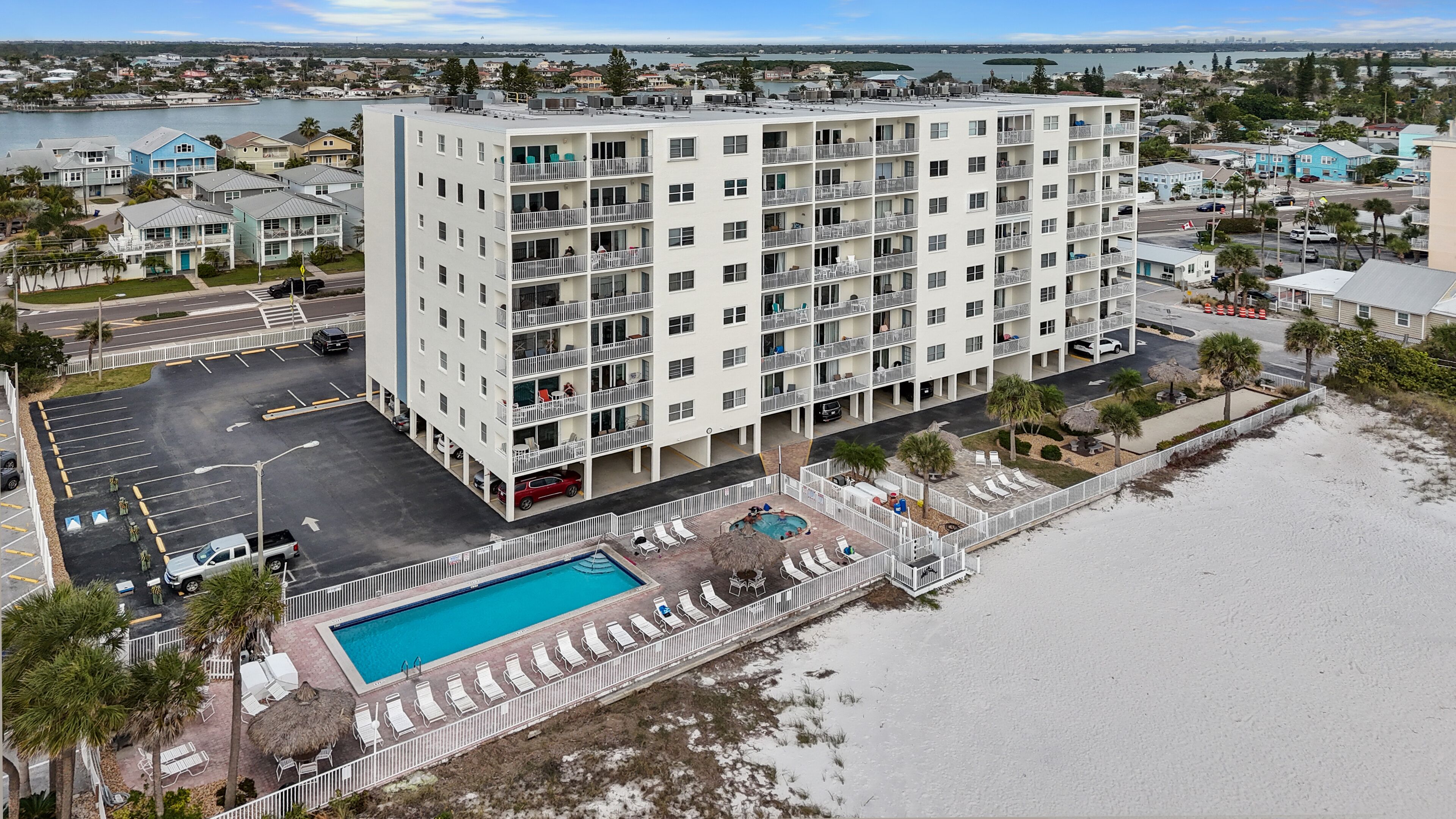 Un hotel de varios pisos con piscina, vista a la playa y estacionamiento.