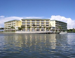 A multi-story hotel with balconies, located near a body of water.