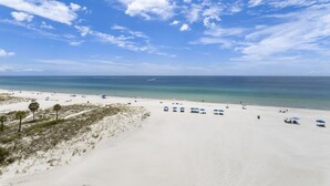 Une plage de sable blanc, un ciel bleu clair et une mer calme.