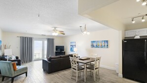 Un salon moderne avec un coin repas, un réfrigérateur noir et un ventilateur de plafond.