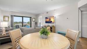 Una sala de estar moderna con una mesa de comedor redonda, un sofá, un televisor y un balcón con vistas.