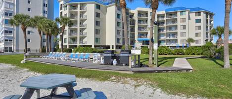 A beachfront hotel with multiple balconies, a barbecue area, and a poolside lounge.