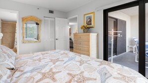 Un dormitorio con cama, cómoda, espejo, puerta y vista al exterior.
