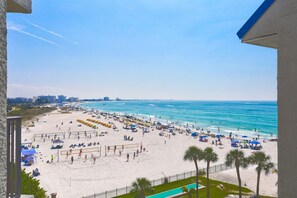 Une plage avec des parasols, des chaises longues et un filet de volley-ball.