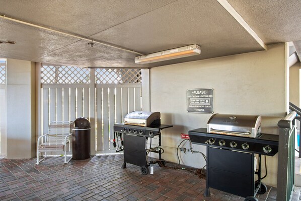 A covered outdoor area with a barbecue grill, a trash can, and a bench. - 🌿 Select View Condo — Gulf Strand Resort, St. Pete Beach (St Pete Beach)