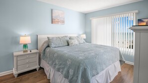Ein Schlafzimmer mit Bett, Nachttisch und Fenster mit Jalousien.