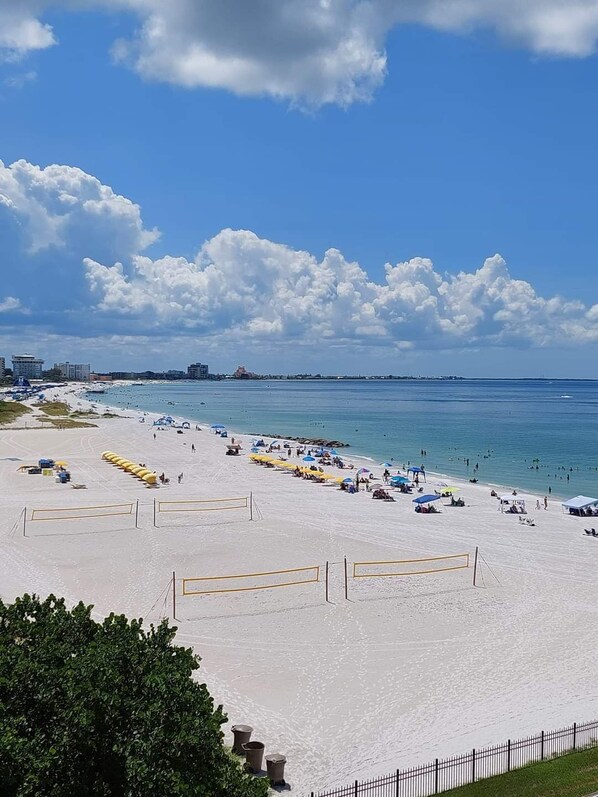 A beach with clear skies, a sandy shore, and a few umbrellas. - 🌊 Caprice Resort Unit #302 – Gulf Front Comfort with Room for Six (St Pete Beach)