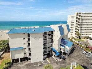 A hotel with a blue roof, a pool, and a view of the ocean. - 🌊 Caprice Resort Unit #302 – Gulf Front Comfort with Room for Six (St Pete Beach)