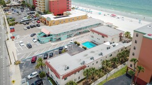 A hotel with a pool, beach view, and parking lot.
