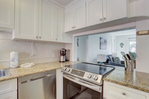 Una cocina moderna con armarios blancos, horno empotrado y lavavajillas.