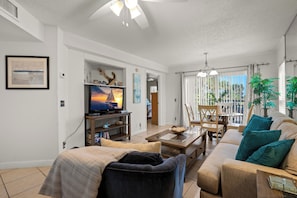 A living room with a television, sofa, coffee table, and dining area.