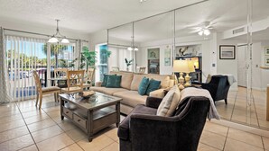 A spacious living room with a large sofa, armchairs, a coffee table, and a dining area with chairs and a table. - 🌿 Select View Condo at Gulf Strand Resort — St. Pete Beach (St Pete Beach)