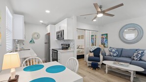 Ein moderner, gut beleuchteter Wohnbereich mit Esstisch, Sofa und Deckenventilator.