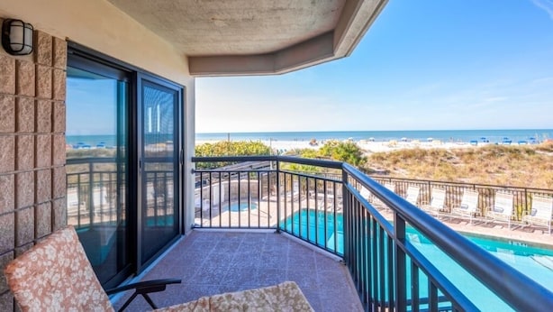 A balcony with a view of the beach and pool. - 🌊 Direct Gulf Front — Gulf Strand Resort, St. Pete Beach (St Pete Beach)