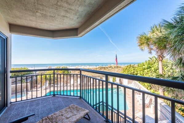 A balcony with a view of a pool and beach.