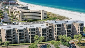 A beachfront hotel with multiple balconies, a parking lot, and a view of the beach and ocean. - 🌊 Direct Gulf Front — Gulf Strand Resort, St. Pete Beach (St Pete Beach)