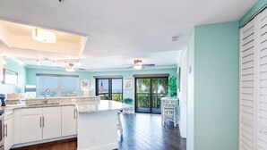 A spacious kitchen with a large island, white cabinetry, and a view to the outdoors. - 🌊 Direct Gulf Front — Gulf Strand Resort, St. Pete Beach (St Pete Beach)