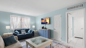 Ein Wohnzimmer mit einem blauen Sofa, einem Glastisch und einem blauen Teppich.