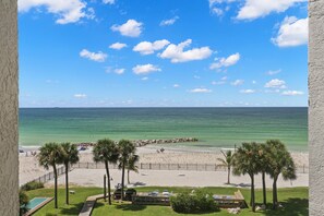 A beach view with a clear sky, palm trees, and a sandy beach. - 🌅 Caprice Resort Unit #403 – Cozy Gulf Front Comfort for Four Guests (St Pete Beach)
