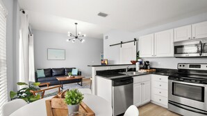 Una cocina moderna con armarios blancos, electrodomésticos de acero inoxidable y una isla central.