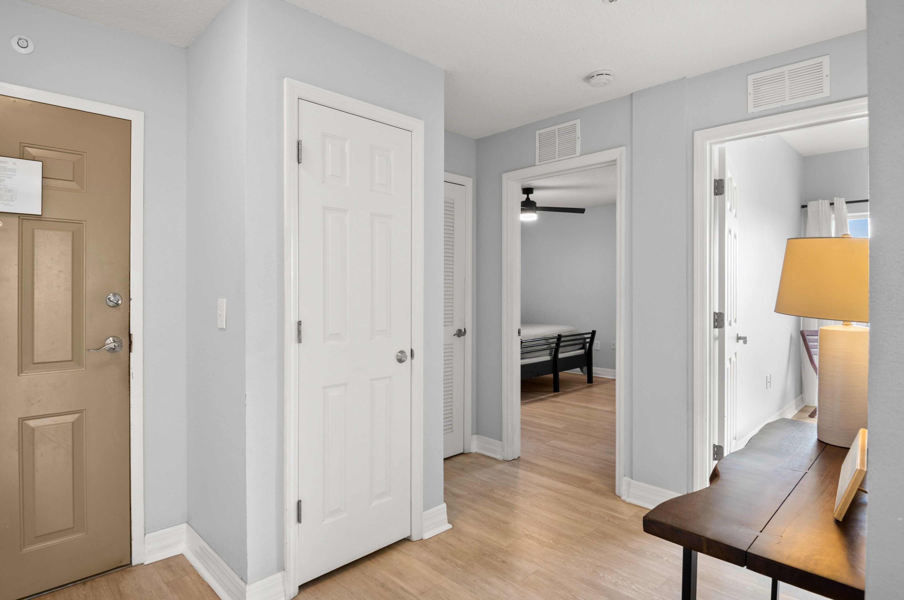 A hallway with two white doors, a bench, and a lamp.