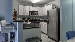 A modern kitchen with white cabinets, stainless steel appliances, and a small island.