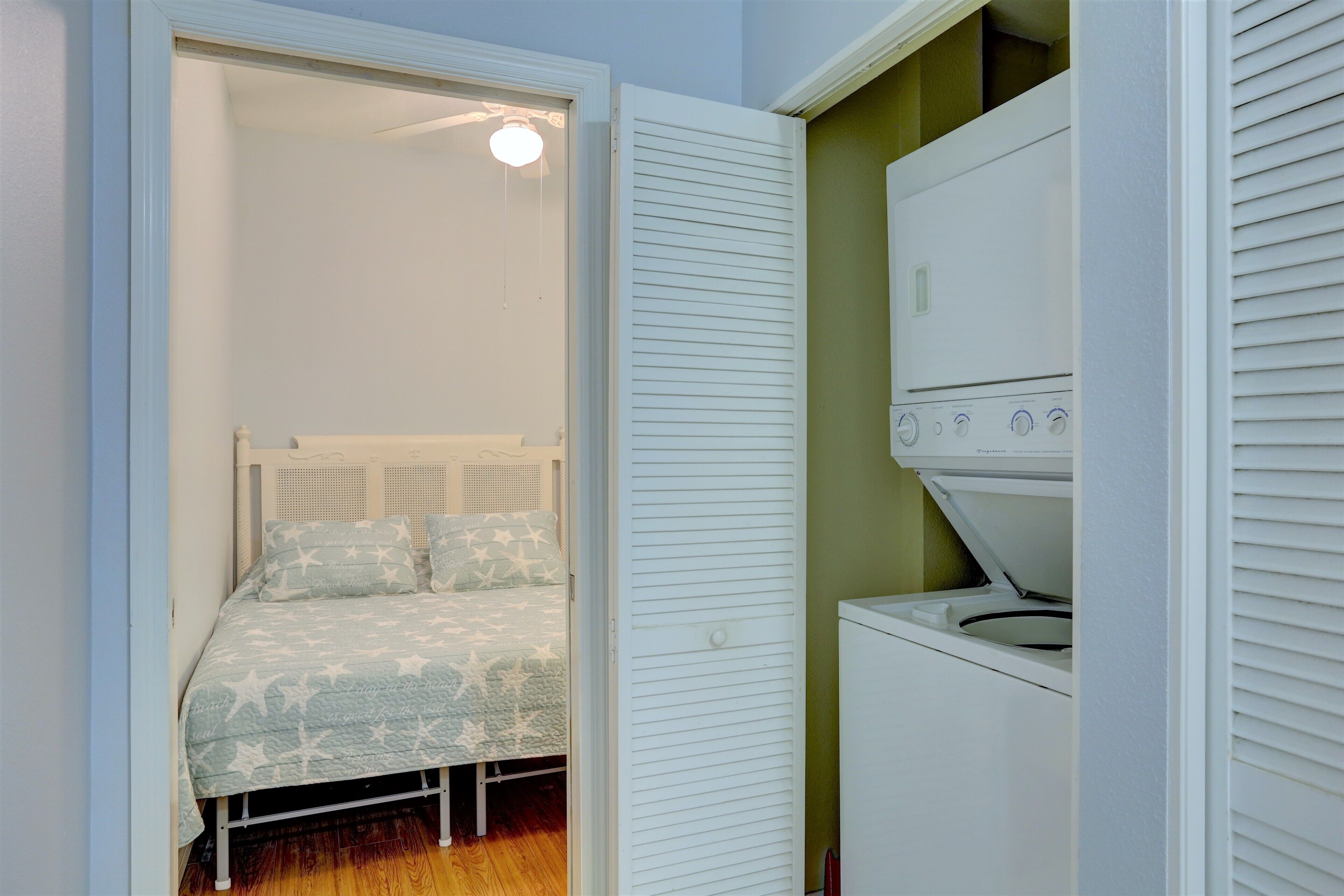 A bedroom with a bed, a ceiling fan, and a washing machine.