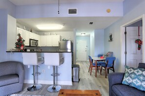 A modern kitchen with white cabinets, a stainless steel refrigerator, and a microwave. There is a small Christmas tree on the counter.