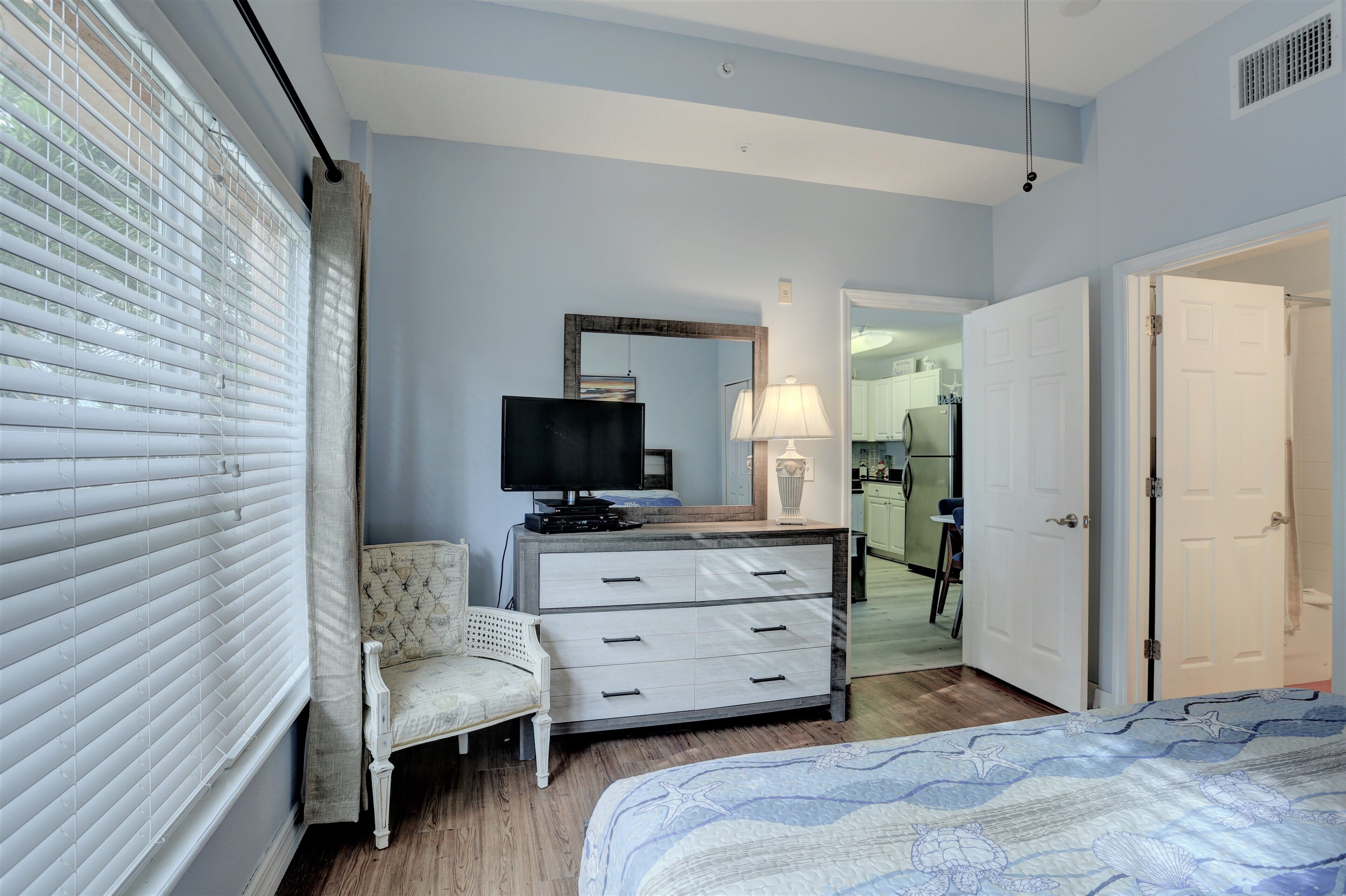 Une chambre à coucher avec un lit, une commode, un téléviseur et une chaise.