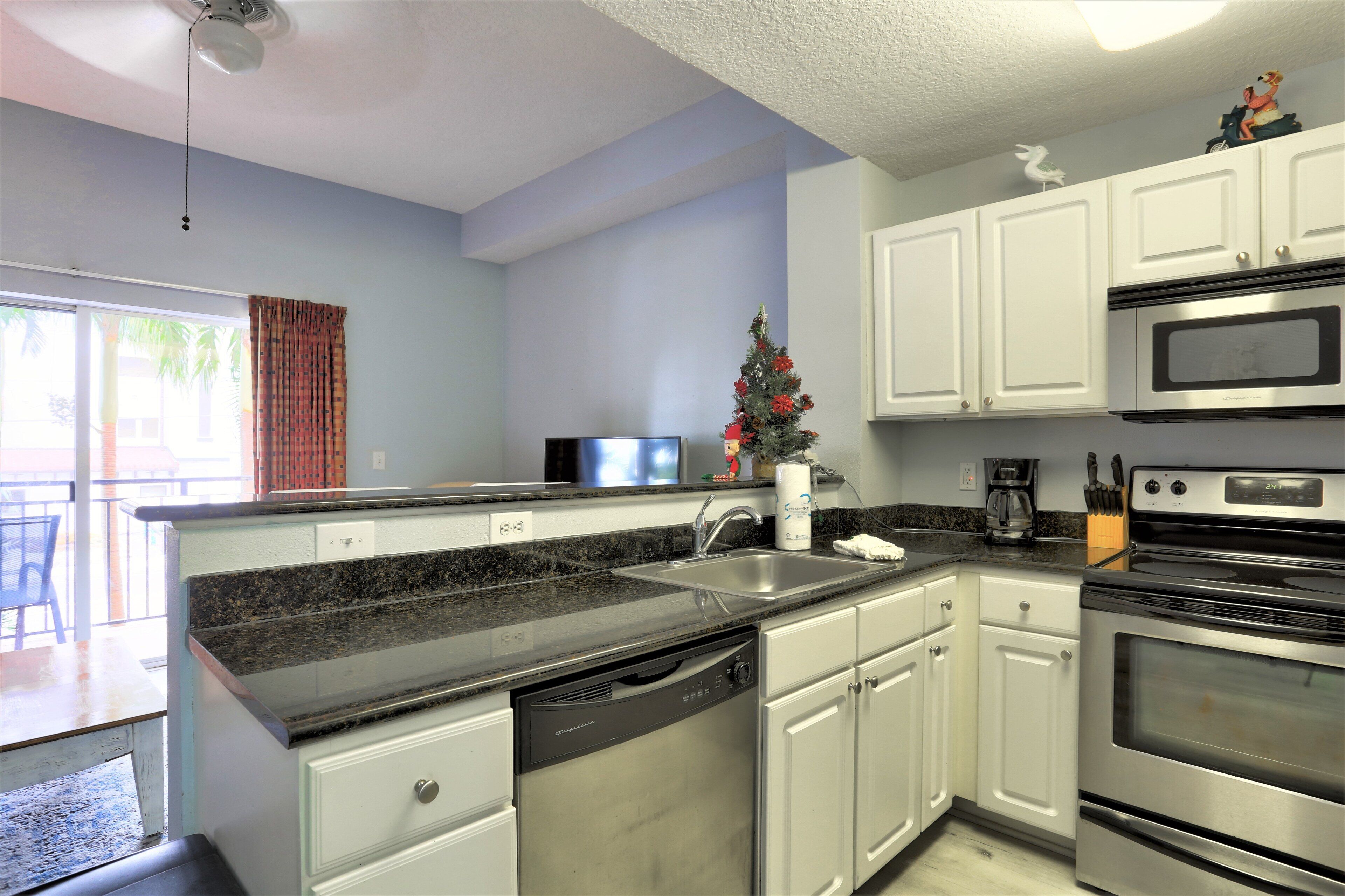 A kitchen with white cabinets, a dishwasher, a microwave, and an oven.