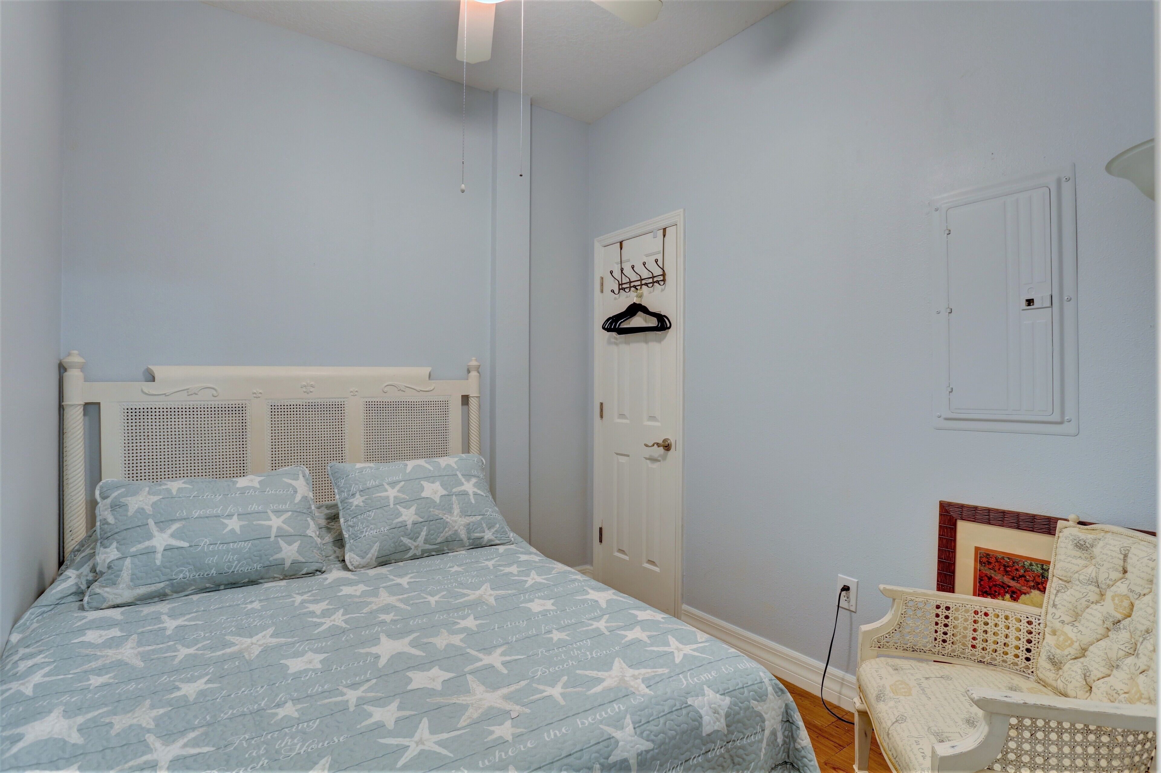 Une chambre à coucher avec un lit, une chaise, une porte et un porte-manteau fixé au mur.