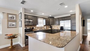 A modern kitchen with granite countertops, stainless steel appliances, and dark cabinetry.