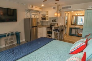 A compact bedroom with a bed, a desk, and a kitchenette. - Redington Surf Resort 01 Quaint Beach Front Condo Motel (North Redington Beach)
