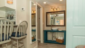 A modern kitchen with a dining area, a blue console table, and a large mirror above the sink.