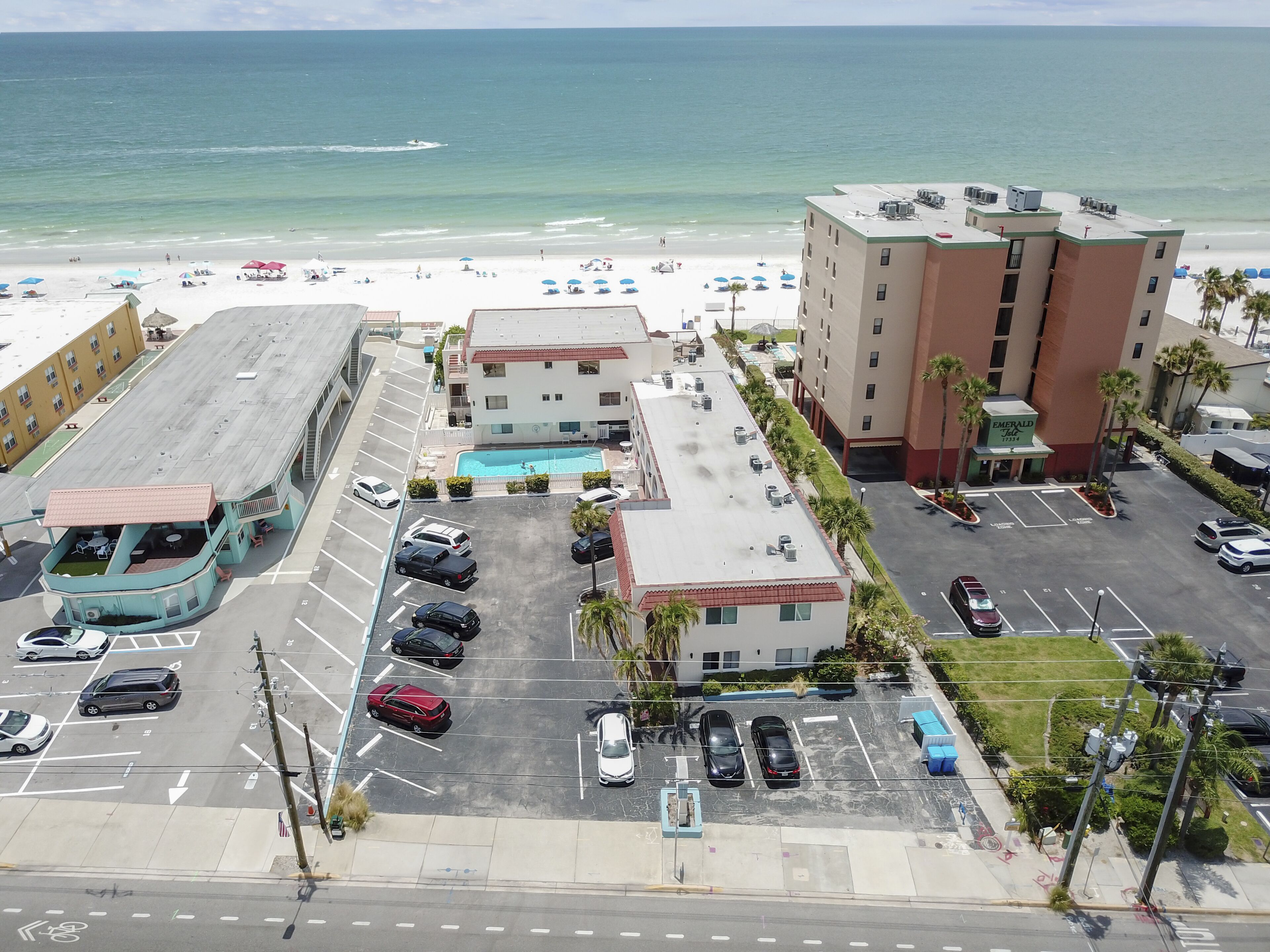 Ein Hotel mit Pool, Parkplatz und Blick auf den Strand.