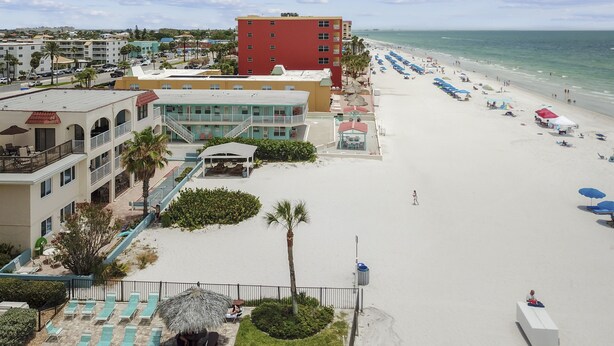 A beachfront hotel with multiple floors, a pool area, and beach umbrellas.