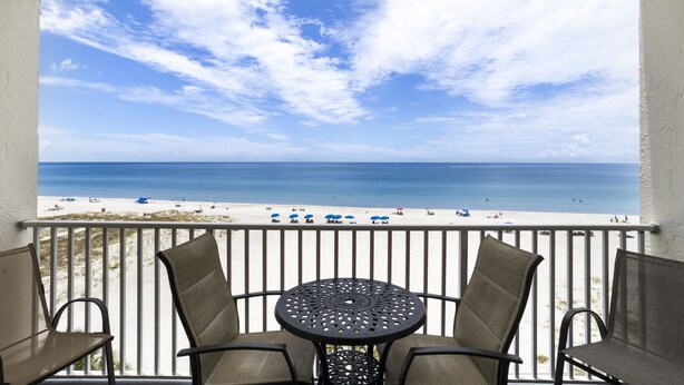 Un balcon avec vue sur la plage, comprenant une table et deux chaises.