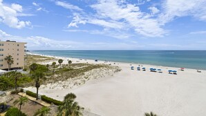 Une plage avec un bâtiment au premier plan, un ciel dégagé et l’océan en arrière-plan.