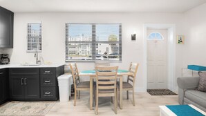 A modern kitchen with dark cabinets, a white countertop, and a dining area with a table and chairs.
