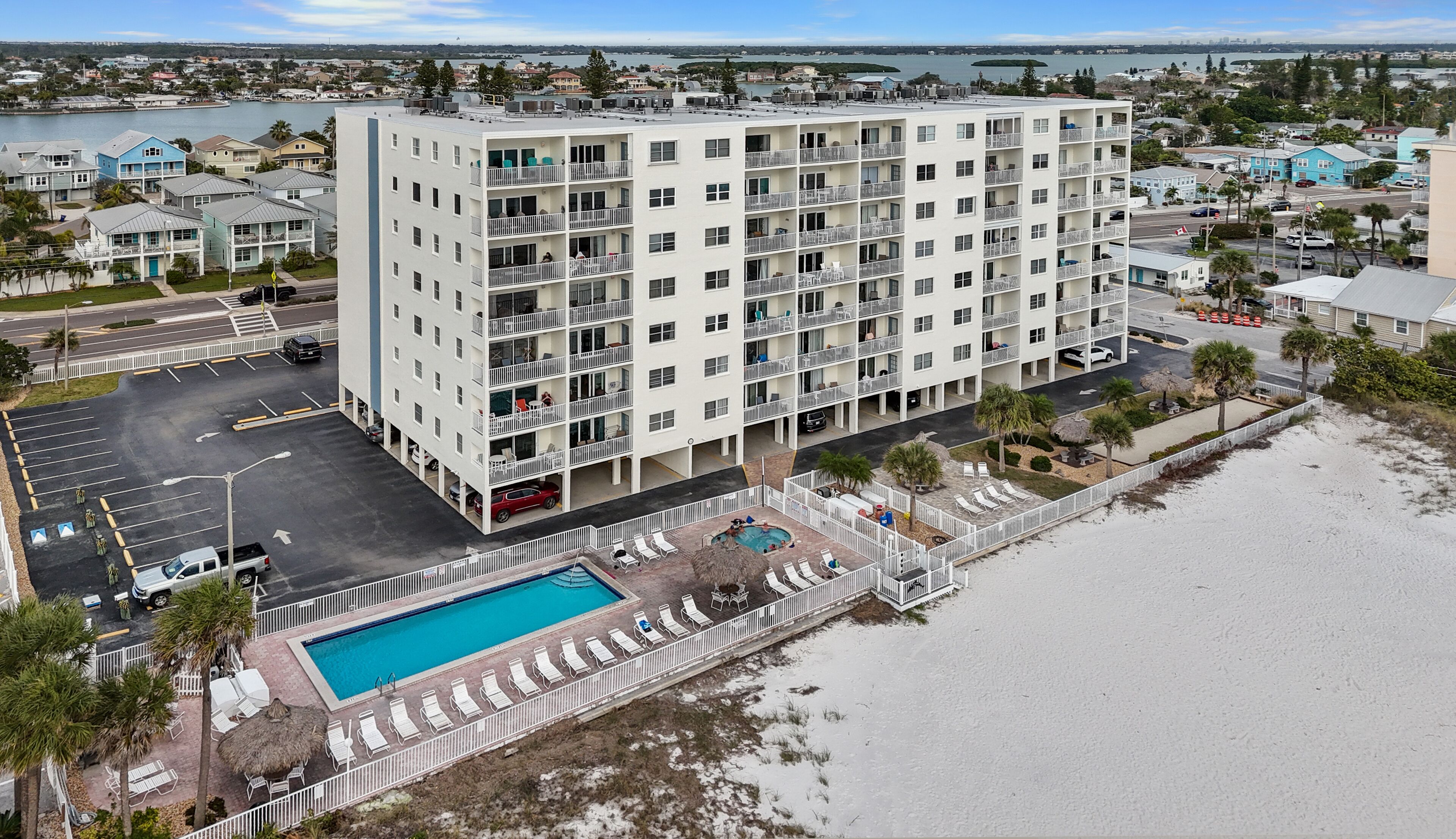 A multi-story hotel with a pool and beachside lounge chairs.
