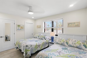 Une chambre avec deux lits, une fenêtre avec des stores, un miroir et une lampe sur une table de chevet.